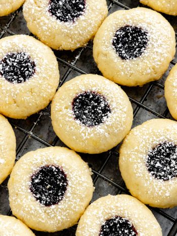 These Jam-Filled Thumbprint Cookies combine soft butter cookies and a sweet jam filling. Use your favorite jelly flavor like blackberry, strawberry, raspberry or other favorites. Add a light dust of powdered sugar for extra flair and these cookies bound to disappear off cookie platters fast. #thumbprintcookies #cookies #jamcookies #olgainthekitchen #dessert #homemade